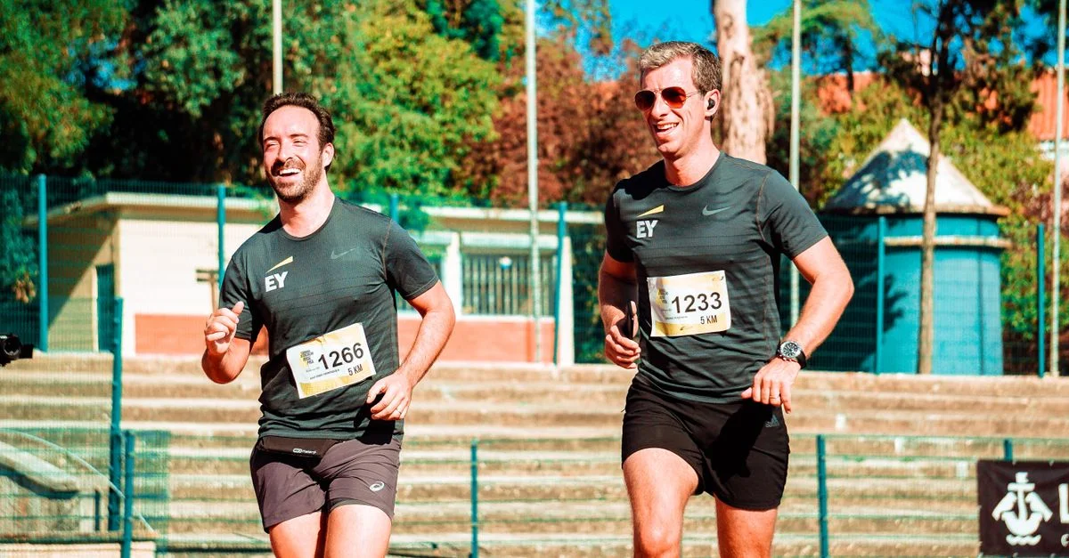 Deux hommes courant lors d'une course de 5 km en extérieur par une journée ensoleillée, mettant en valeur la forme physique et l'endurance.