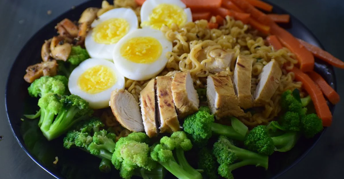Délicieux plat de nouilles avec du poulet, du brocoli, des œufs et des carottes, parfait pour un repas sain.