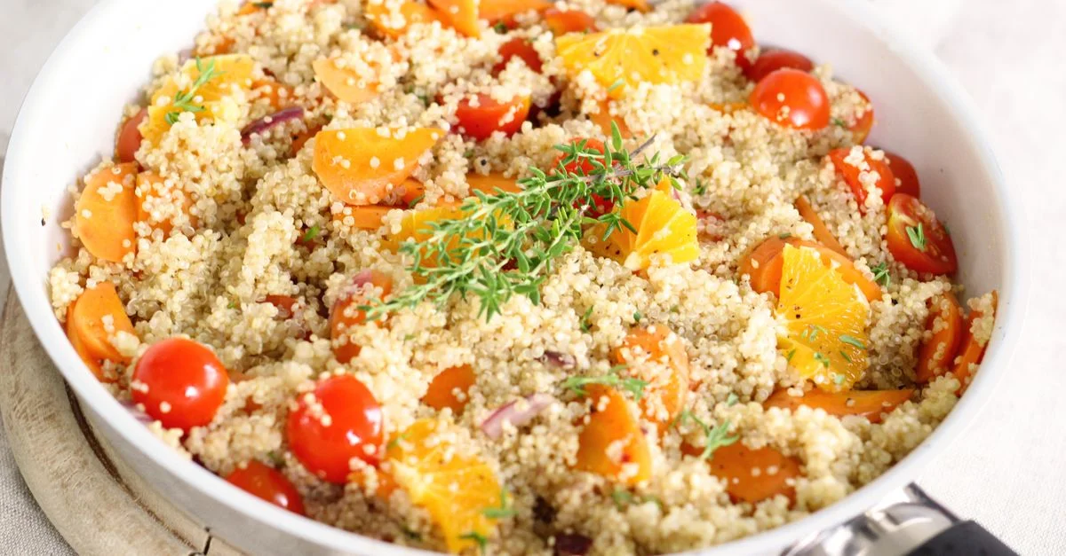 Délicieuse salade de quinoa vegan avec des tomates, des oranges et des herbes fraîches.
