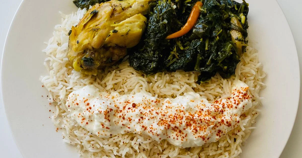 Gros plan sur un plat savoureux de poulet servi avec du riz et des légumes dans une assiette.