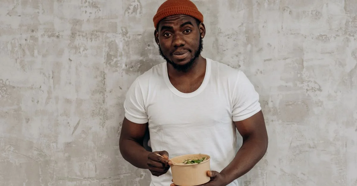 Homme souriant en T-shirt blanc appréciant un repas sain à l'intérieur, incarnant un mode de vie sain.