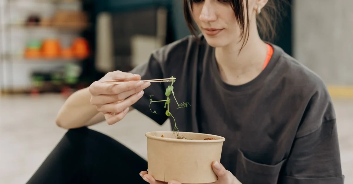 Jeune femme savourant une salade saine à l'intérieur, mettant l'accent sur une nutrition équilibrée et un mode de vie sain.
