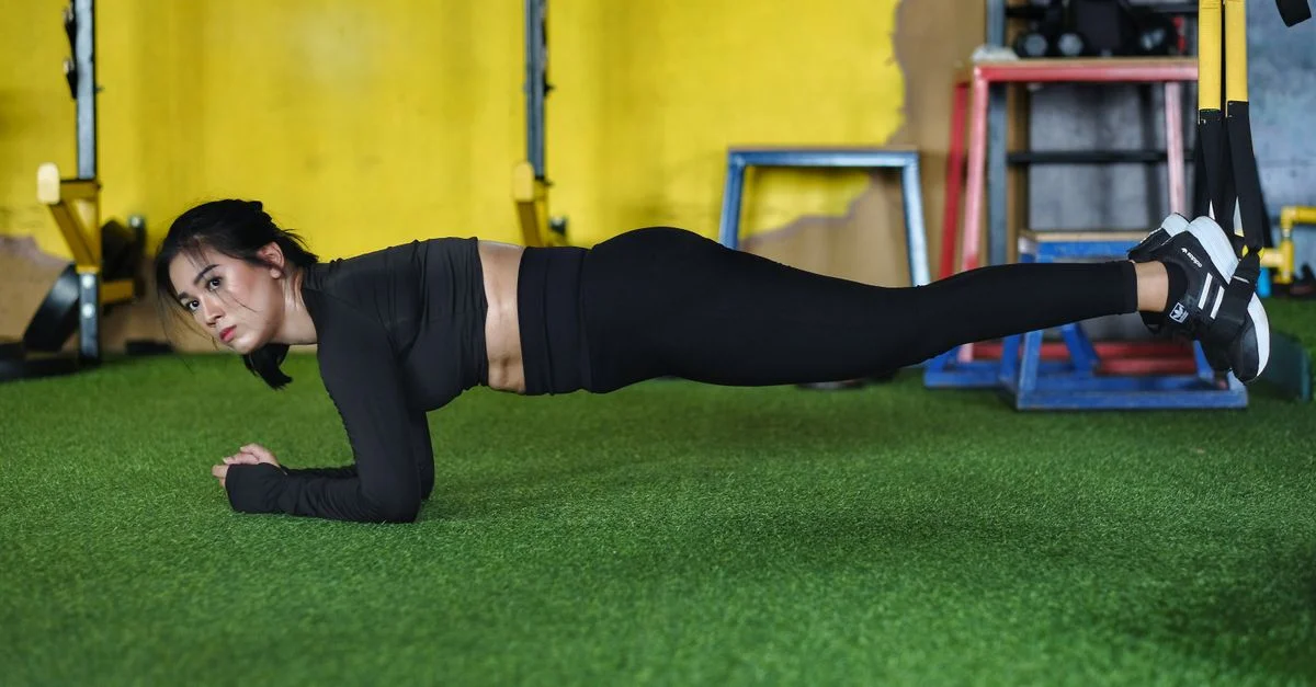 Femme concentrée effectuant un entraînement TRX dans une salle de sport de Garut. Entraînement de force et d'équilibre en intérieur.